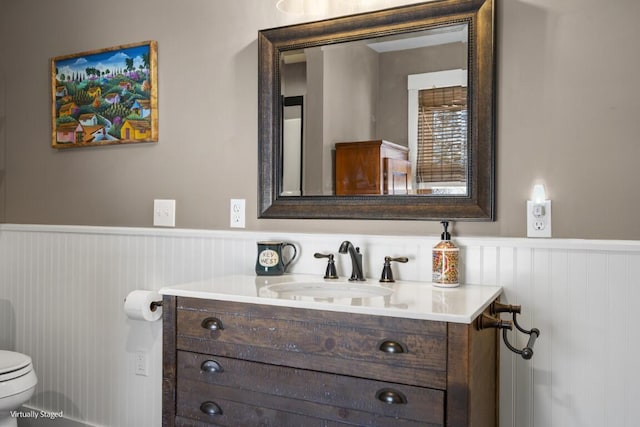 bathroom with a wainscoted wall, toilet, and vanity