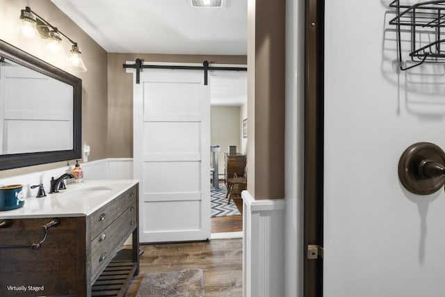 bathroom with a wainscoted wall, visible vents, vanity, and wood finished floors