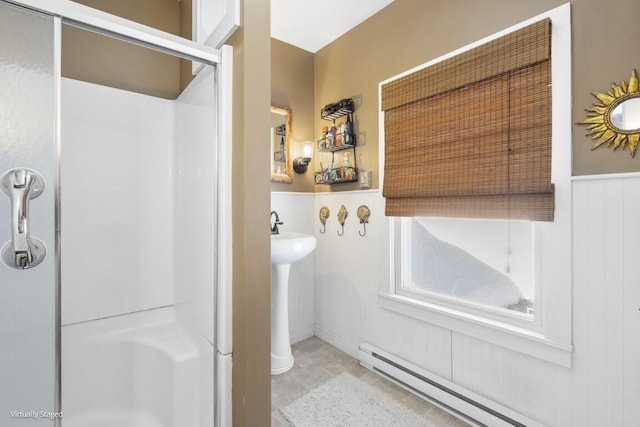 bathroom with a baseboard heating unit, a wainscoted wall, a shower stall, and toilet