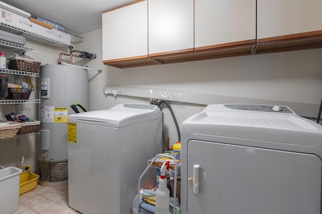 laundry area with cabinet space, light tile patterned floors, a textured ceiling, washing machine and dryer, and water heater