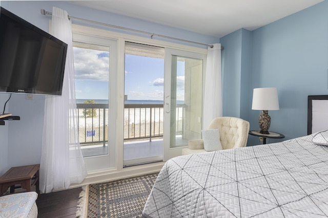 bedroom with a water view, wood finished floors, and access to exterior