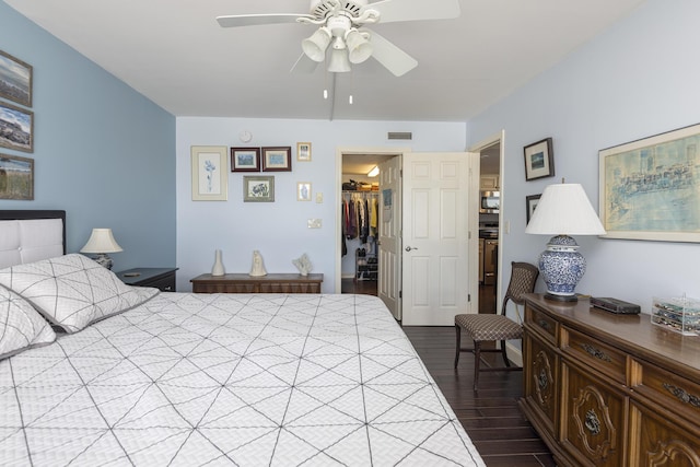 bedroom featuring a walk in closet, dark wood finished floors, a closet, visible vents, and ceiling fan