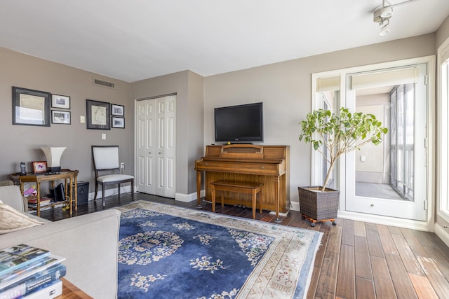 living area with wood finished floors, visible vents, and baseboards