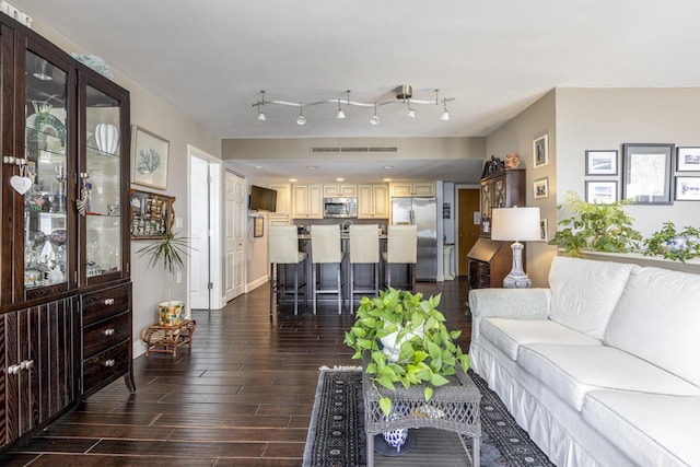 living room featuring dark wood-type flooring, visible vents, and track lighting