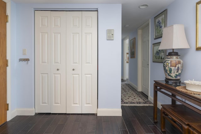 hall featuring dark wood-type flooring and baseboards