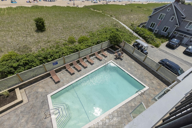 community pool with a patio area and fence