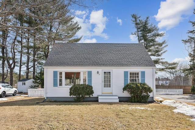 view of front of home with entry steps, a front yard, fence, and roof with shingles