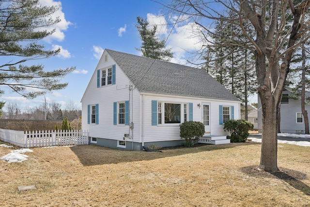 view of front of house featuring a front yard, fence, and a shingled roof