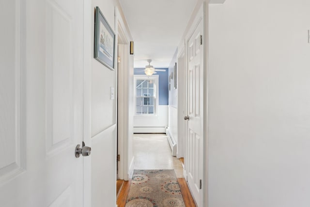 hallway with a baseboard heating unit and light wood finished floors