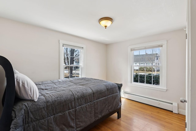 bedroom featuring baseboard heating and wood finished floors