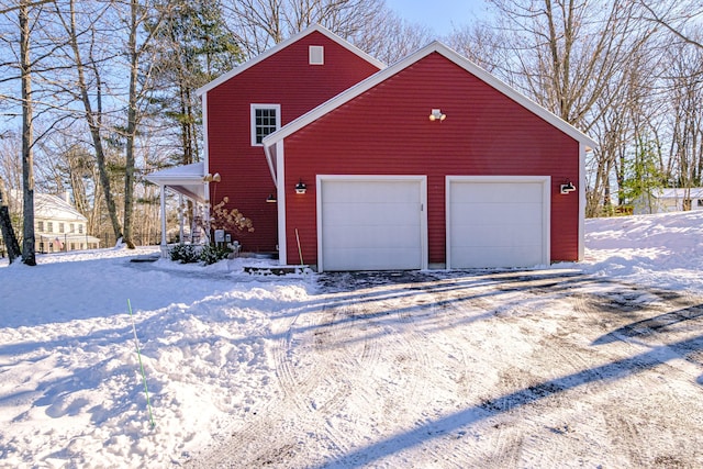 snow covered garage with driveway