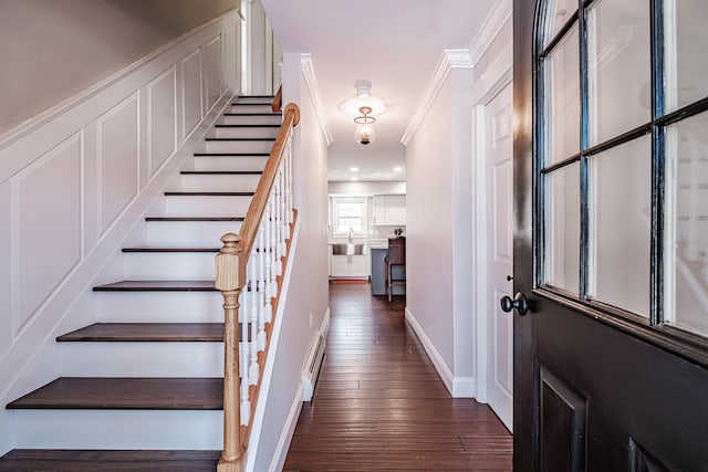 entrance foyer with dark wood-style floors, crown molding, a baseboard radiator, baseboards, and stairs