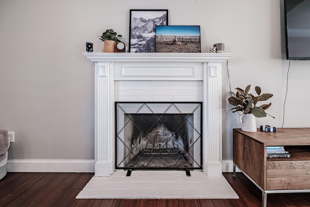 room details featuring a fireplace with flush hearth, baseboards, and wood finished floors