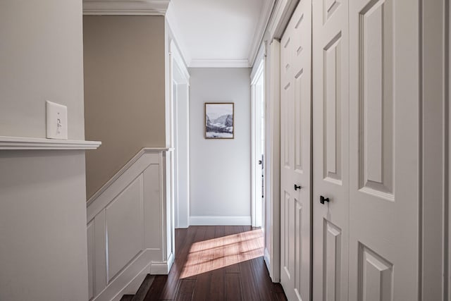 hallway featuring baseboards, ornamental molding, and dark wood finished floors