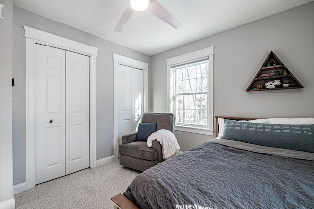 carpeted bedroom with a ceiling fan, baseboards, and multiple closets