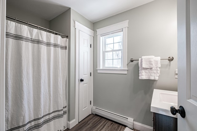 full bath featuring a shower with shower curtain, wood finished floors, vanity, baseboards, and baseboard heating