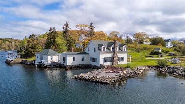 rear view of house featuring a water view, a chimney, and a yard