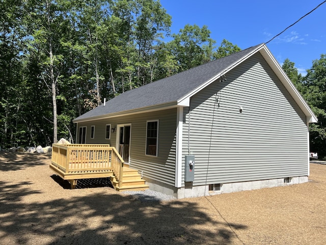 exterior space featuring a shingled roof and a deck