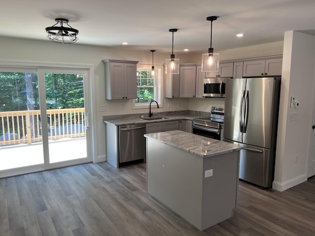 kitchen with gray cabinetry, a sink, light stone counters, wood finished floors, and appliances with stainless steel finishes