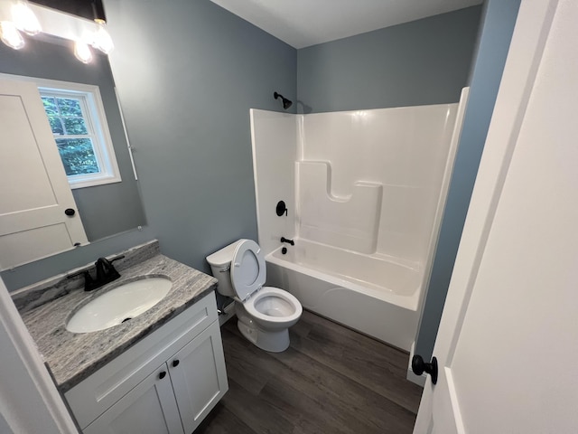 bathroom with toilet, vanity,  shower combination, and wood finished floors