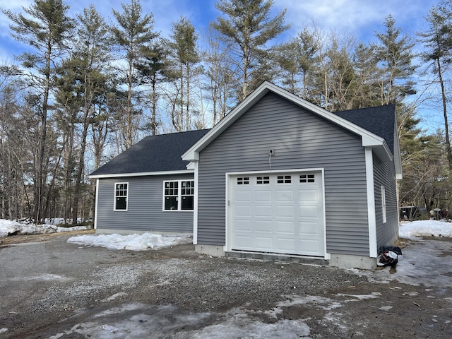 exterior space featuring a garage and roof with shingles