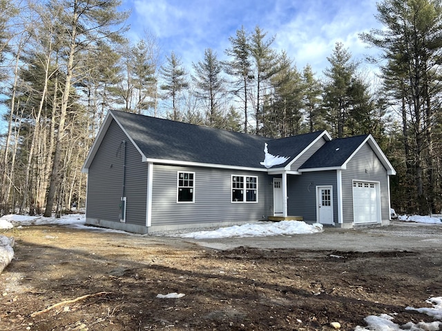 ranch-style home featuring an attached garage and a shingled roof