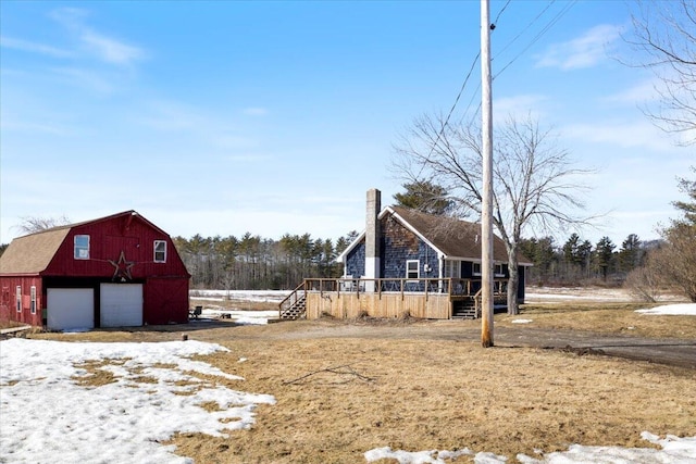 yard layered in snow with a barn, a detached garage, and an outdoor structure