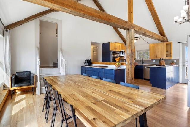 dining area featuring stairs, beam ceiling, light wood-style floors, an inviting chandelier, and high vaulted ceiling