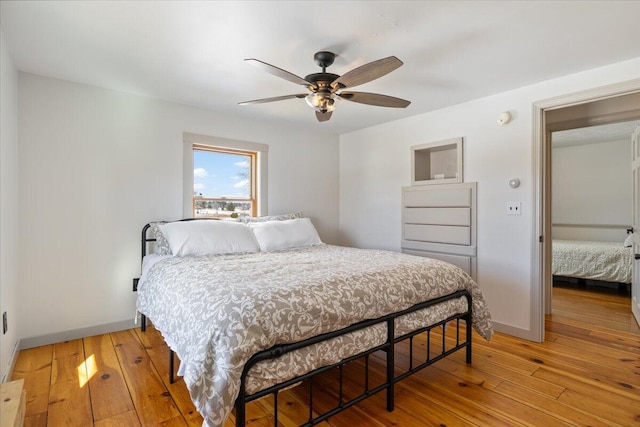 bedroom with ceiling fan, baseboards, and light wood-style flooring