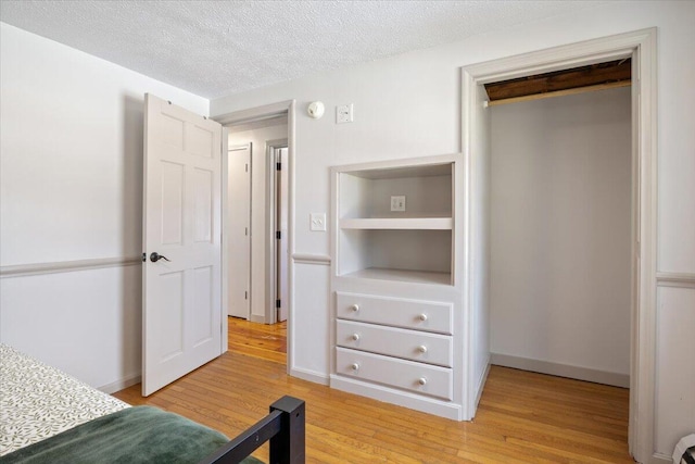 unfurnished bedroom featuring baseboards, a textured ceiling, and light wood finished floors