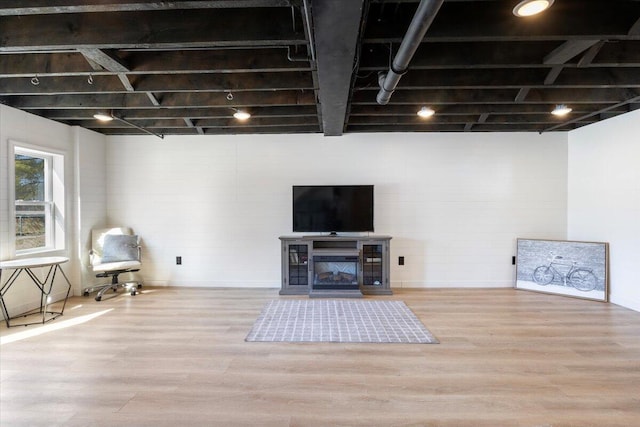 below grade area featuring a glass covered fireplace and wood finished floors