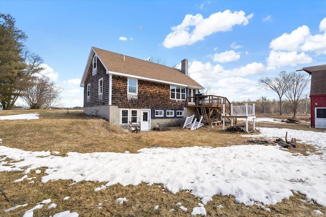 snow covered property featuring a wooden deck, stairway, and a chimney