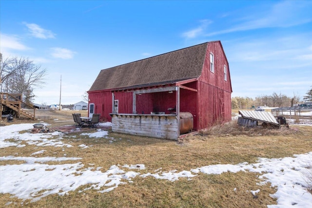 snow covered structure with a barn and an outbuilding