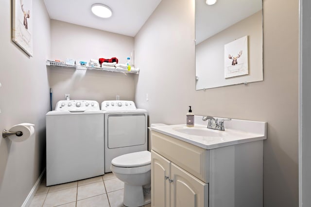 half bathroom featuring washing machine and dryer, toilet, vanity, baseboards, and tile patterned floors