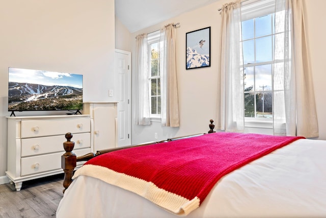 bedroom with vaulted ceiling, multiple windows, and wood finished floors
