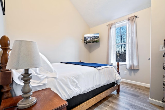 bedroom with lofted ceiling, wood finished floors, and baseboards
