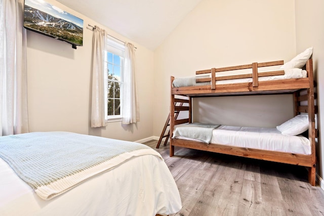 bedroom featuring lofted ceiling, baseboards, and wood finished floors
