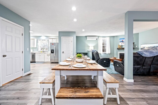 dining area with a wall unit AC, light wood-type flooring, baseboards, and recessed lighting
