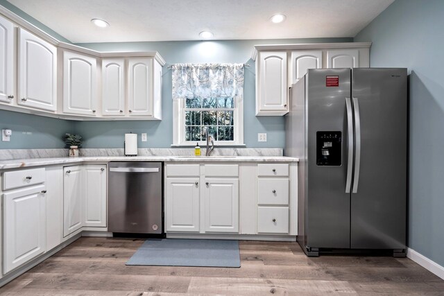 kitchen with light wood-style floors, appliances with stainless steel finishes, light countertops, and a sink