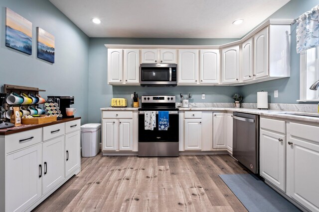 kitchen featuring recessed lighting, a sink, white cabinets, appliances with stainless steel finishes, and light wood finished floors