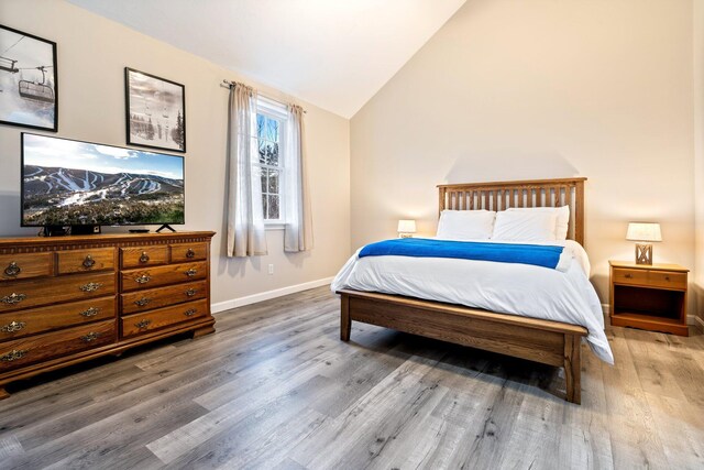 bedroom featuring lofted ceiling, baseboards, and wood finished floors