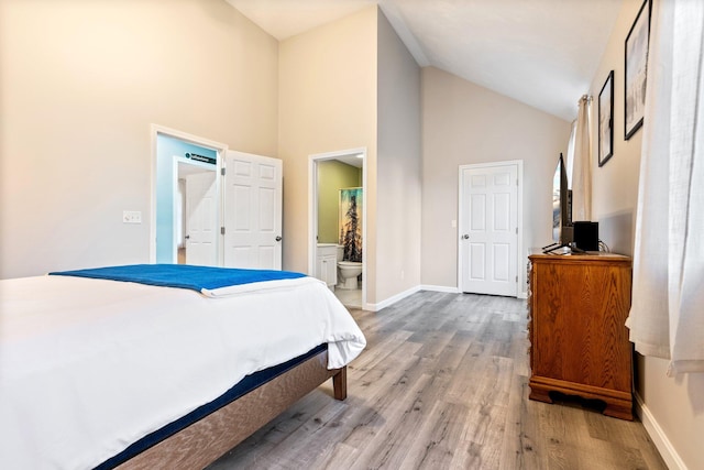 bedroom featuring light wood-style floors, ensuite bath, high vaulted ceiling, and baseboards
