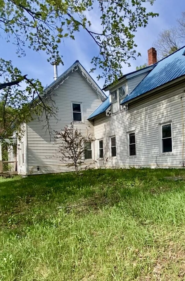 back of house with metal roof and a chimney