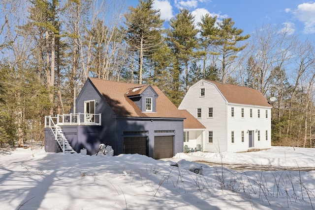 view of front facade with a garage, roof with shingles, a deck, and stairs