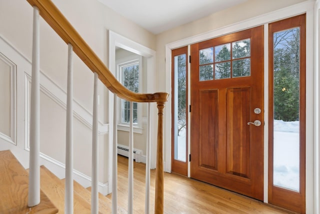 foyer with a baseboard heating unit, stairs, and light wood-style floors