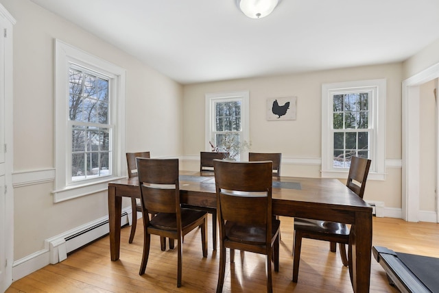 dining room featuring light wood-type flooring, a healthy amount of sunlight, and baseboard heating