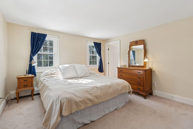 bedroom featuring light carpet, baseboards, and a baseboard heating unit