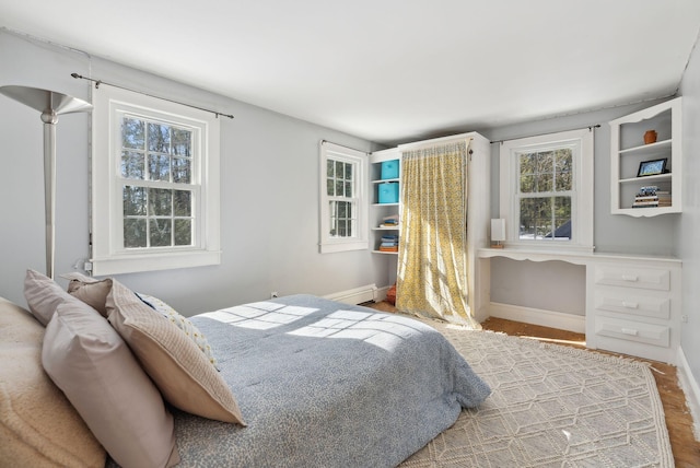 bedroom featuring baseboards, baseboard heating, and wood finished floors