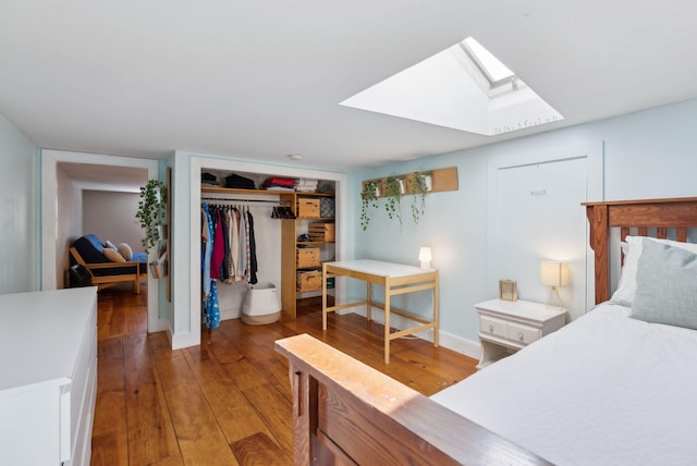 bedroom featuring a closet, light wood-type flooring, a skylight, and baseboards