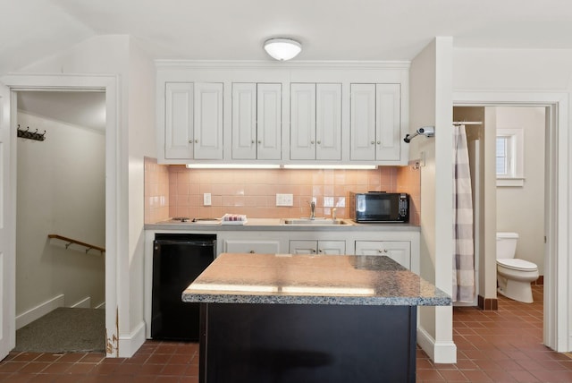 kitchen featuring black microwave, white cabinetry, a sink, and decorative backsplash